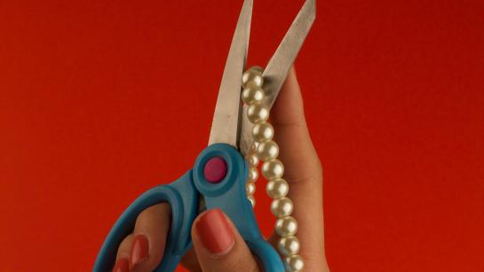 scissors cutting a pearl necklace