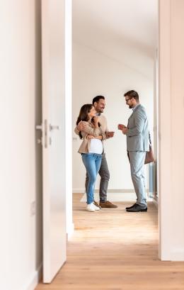 Young white couple talking with a white real-estate agent visiting an apartment for sale or for rent.