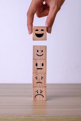 Hand putting wooden cube block with smiley icon