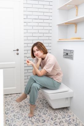 Portrait of stressing woman sits in the lavatory and holds pregnancy test in her hand 