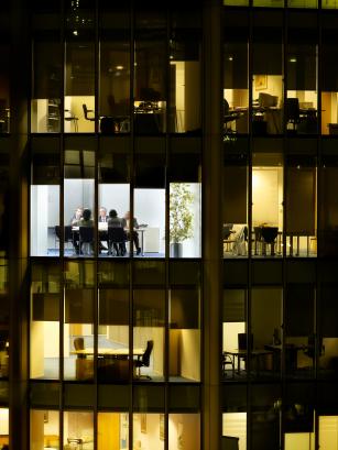 Business meeting viewed through illuminated window of office block at night